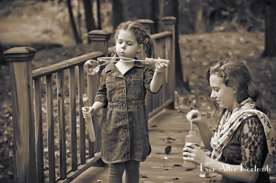 Two sisters blowing bubbles on bridge.